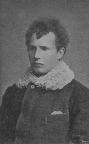 Czarno-biały, lekko ziarnisty portret młodego człowieka w kurtce z futrzanym kołnierzem.