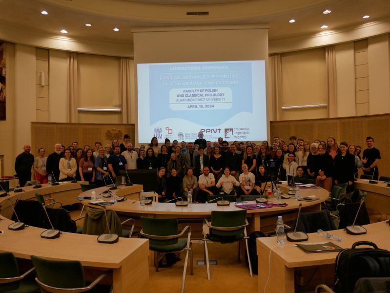 Zdjęcie grupowe uczestników konferencji o języku migowym, stojący w Salonie Mickiewicza.