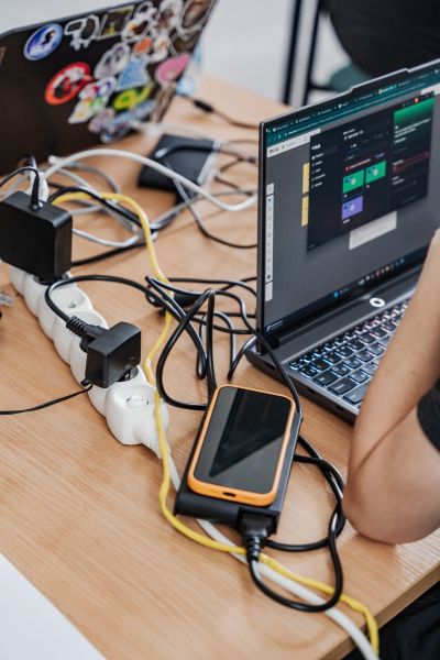 Na stole stoją laptopy i poplątane kable.