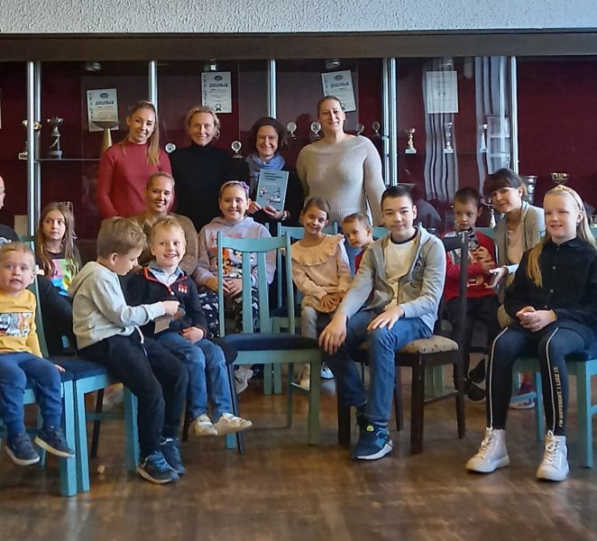 Zdjęcie grupowe uczestników zajęć w Szkole Polskiej w Belgradzie, siedzących rzędem na krzesłach i stojących w sali wykładowej.
