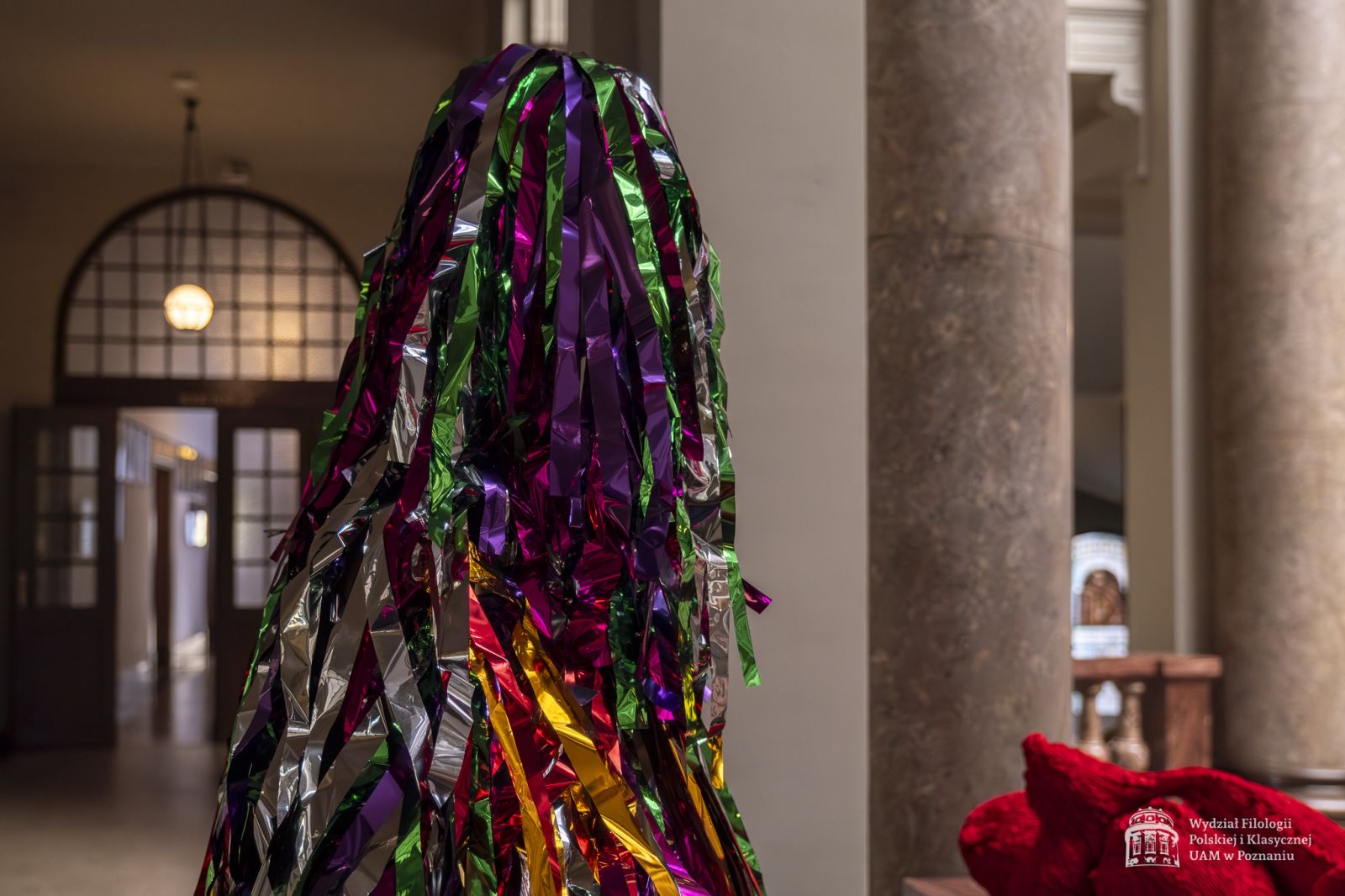 Zdjęcie manekinów w kolorowych, fantazyjnych kostiumach, stojących w holu Collegium Maius.