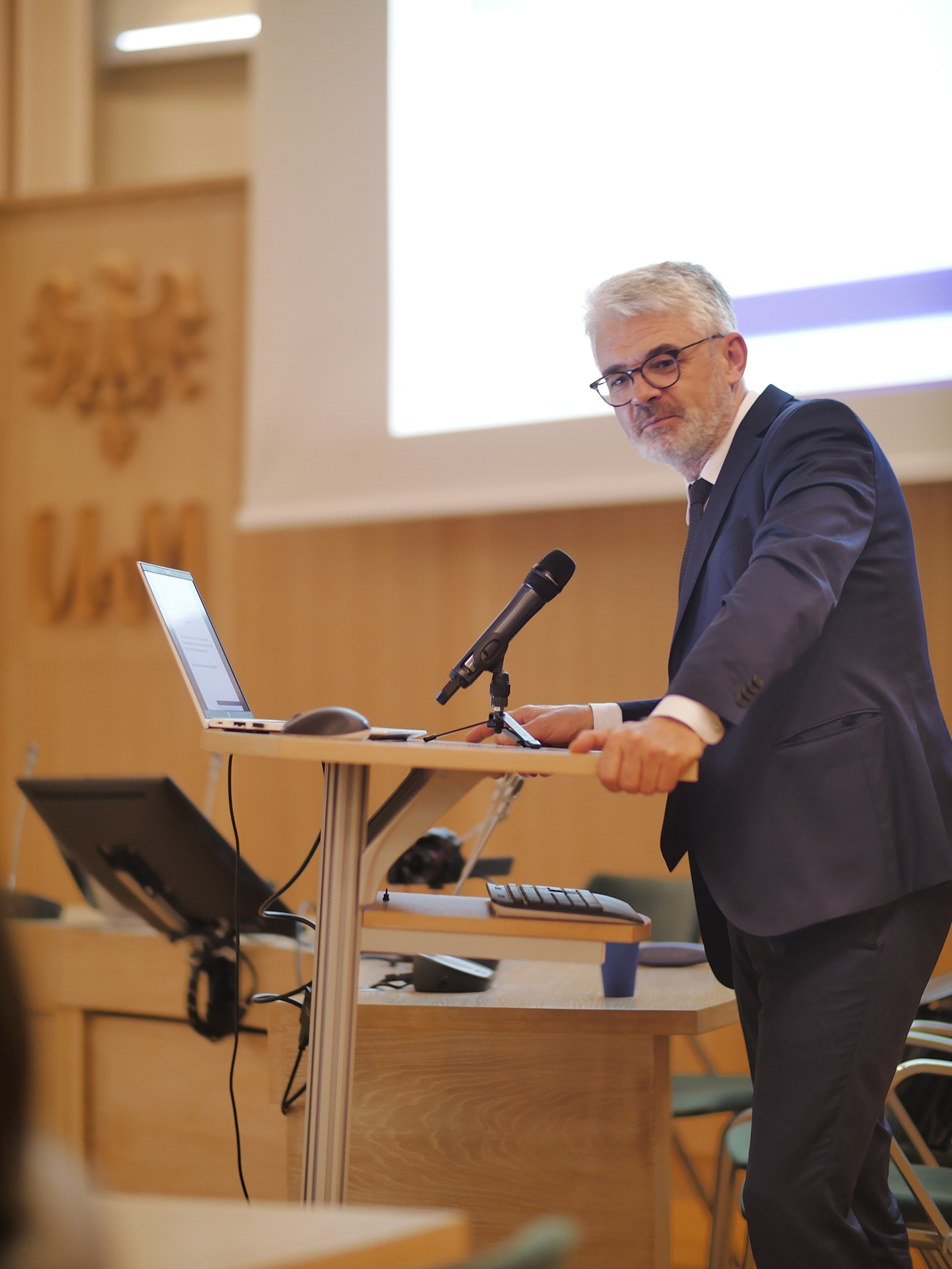 Prodziekan ds. nauki prof. Jerzy Borowczyk stoi przy mównicy, patrzy z uśmiechem w obiektyw, przed nim na pulpicie leży otwarty laptop.