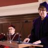 Prof. Krystyna Bartol w fioletowej todze i birecie przemawia za pulpitem do mikrofonu.