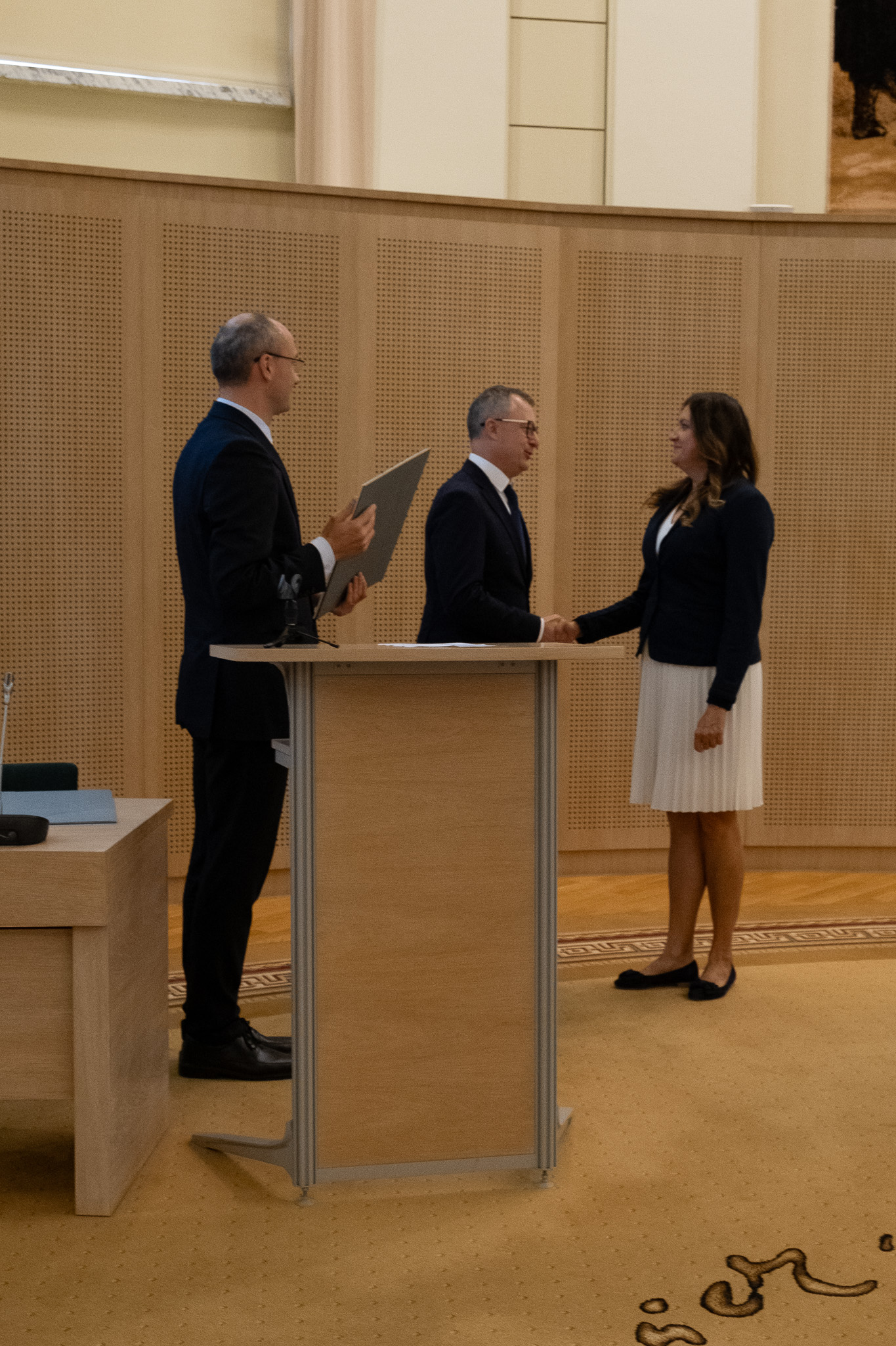 Prof. Tomasz Mizerkiewicz ściska dłoń dr Marlenie Puk, obok stoi prof. Krzysztof Skibski, gotowy by wręczyć nagrodę laureatce.