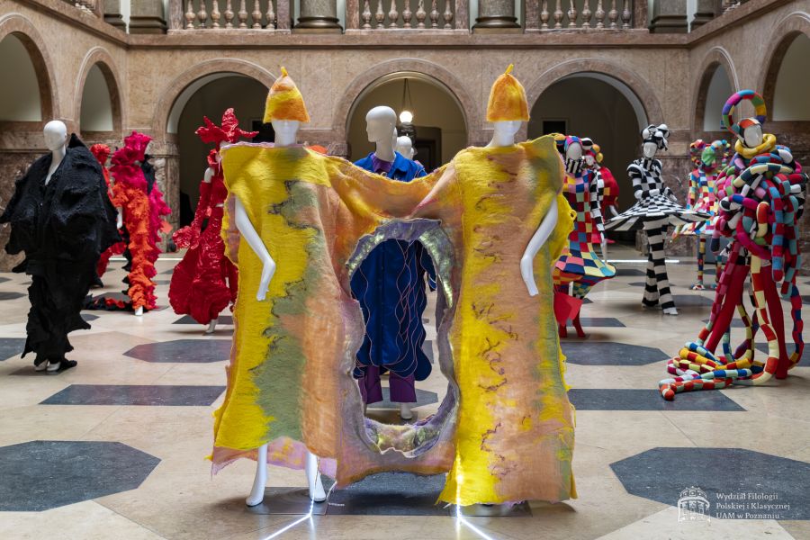 Zdjęcie manekinów w kolorowych, fantazyjnych kostiumach, stojących w holu Collegium Maius.