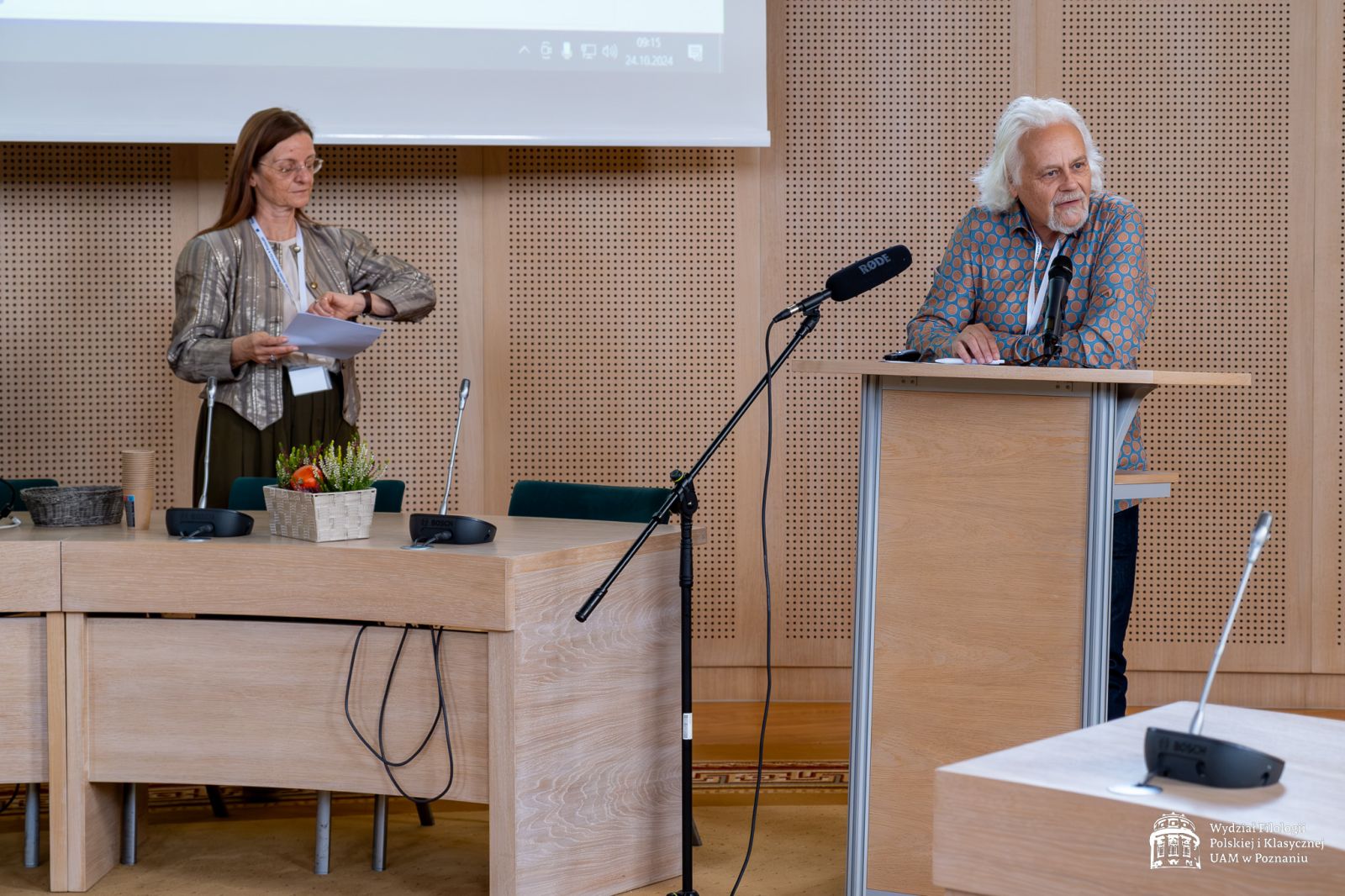 Organizatorzy konferencji przemawiający przy mównicy.