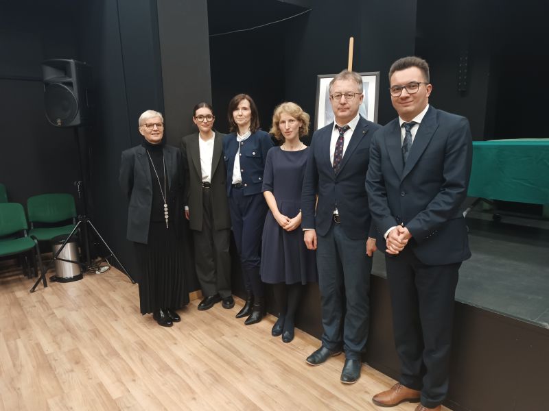 Laureatki tegorocznej edycji konkursu oraz laureat edycji zeszłorocznej stoją wraz prof. Agatą Stankowską-Balcerzan, prof. Elżbietą Winiecką i prof. Tomaszem Mizerkiewiczem na tle sceny z plakatem ze zdjęciem prof. Czesława Zgorzelskiego, pozując z uśmiechem do pamiąkowego zdjęcia.