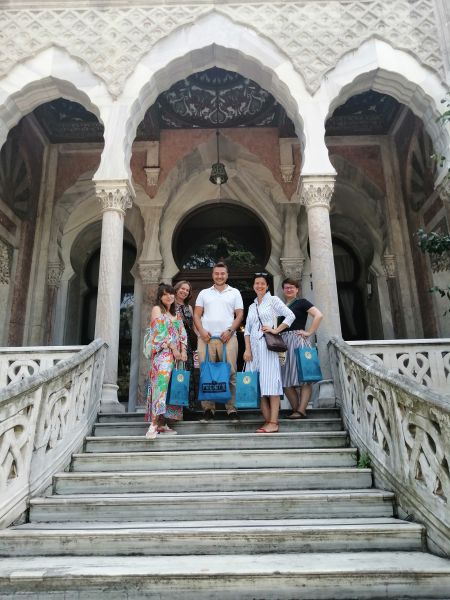 Na schodach prowadzących do budynku z białego kamienia w stylu orientalnym stoi grupa osób - 4 kobiety i mężczyzna.