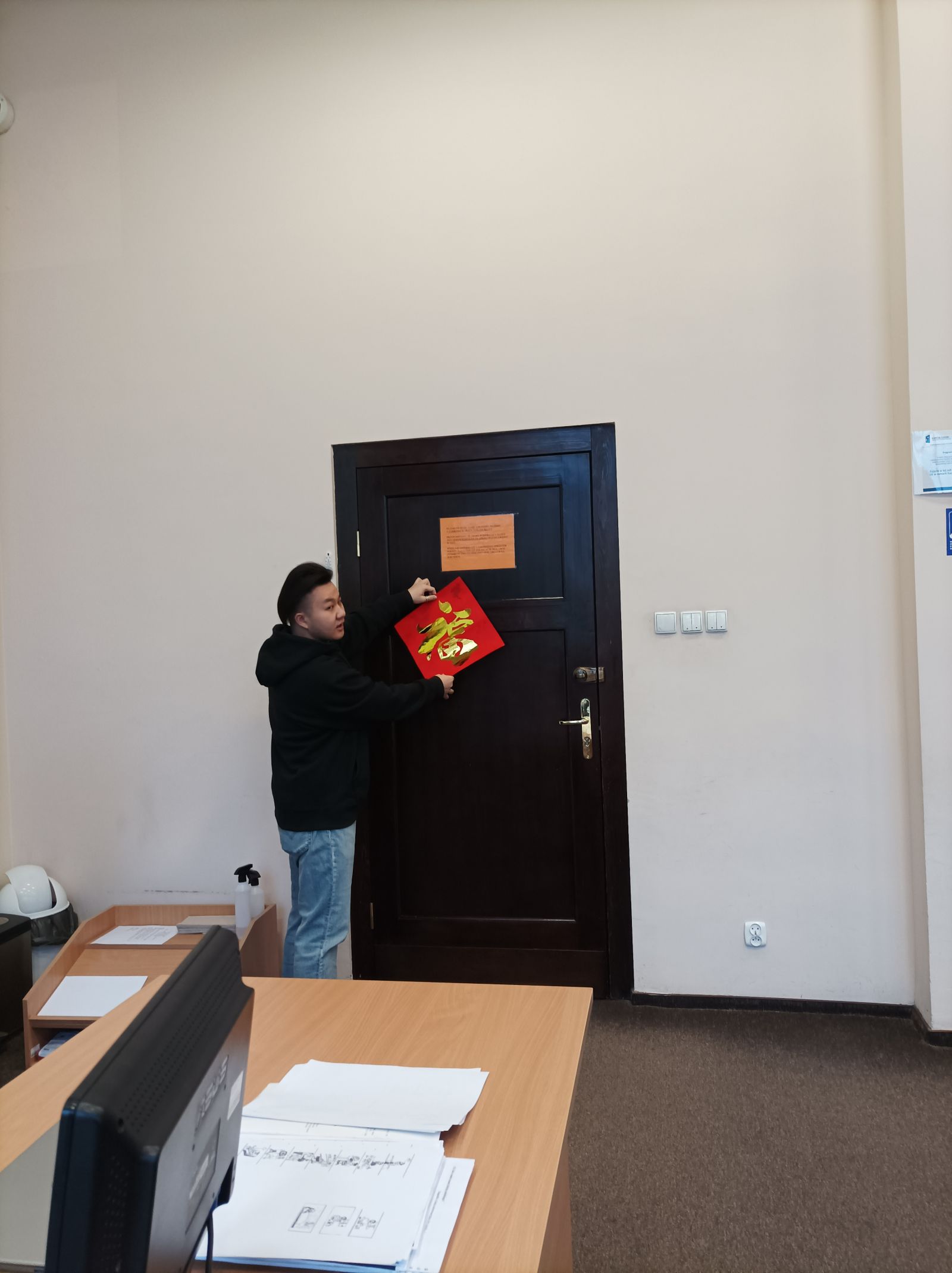 Student z Chin przywiesza czerwoną kopertę na drzwiach.