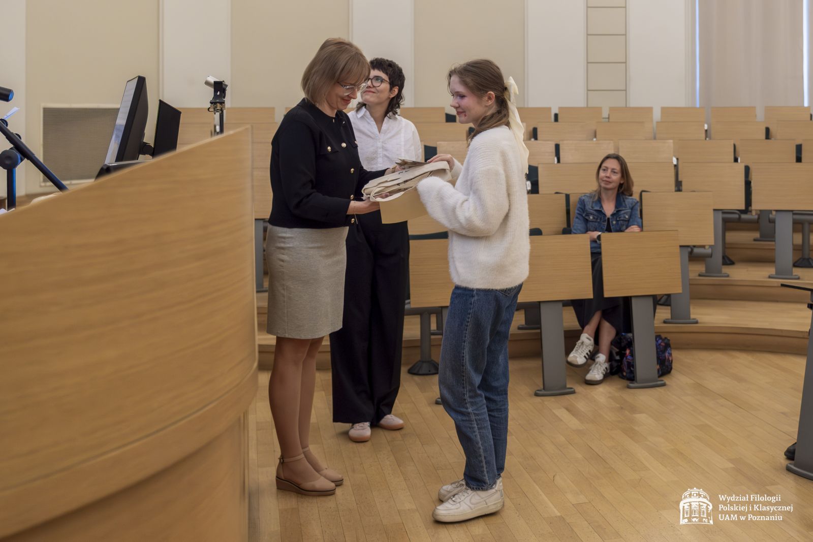 Dwie członkinie jury wręczają nagrody studentce.