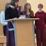 Przy mównicy w Salonie Mickiewicza stoi uczennica i odczytuje swoje wystąpienie, za nią stoją inni uczniowie i uczennice.