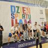 Drużyna siatkarska stoi na szczycie podium, ciesząc się z pucharu.