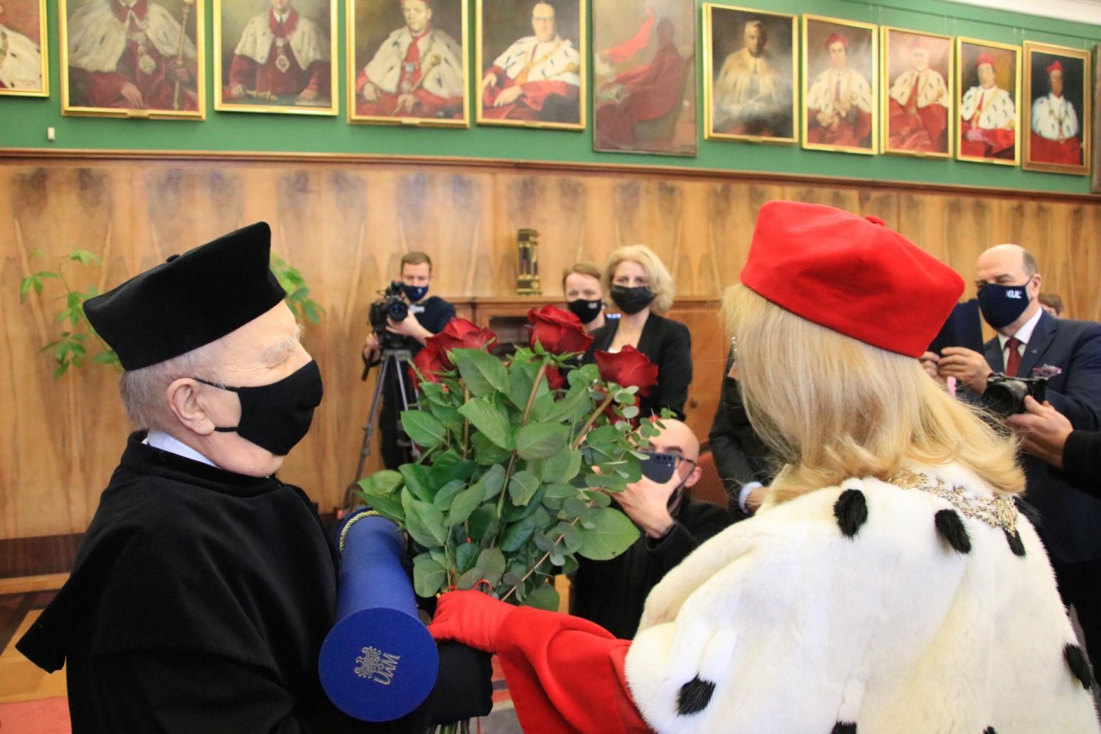 Zdjęcie z uroczystości nadania doktoratu honoris causa prof. Henrykowi Podbielskiemu. Rektor UAM wręcza profesorowi bukiet czerwonych róż.