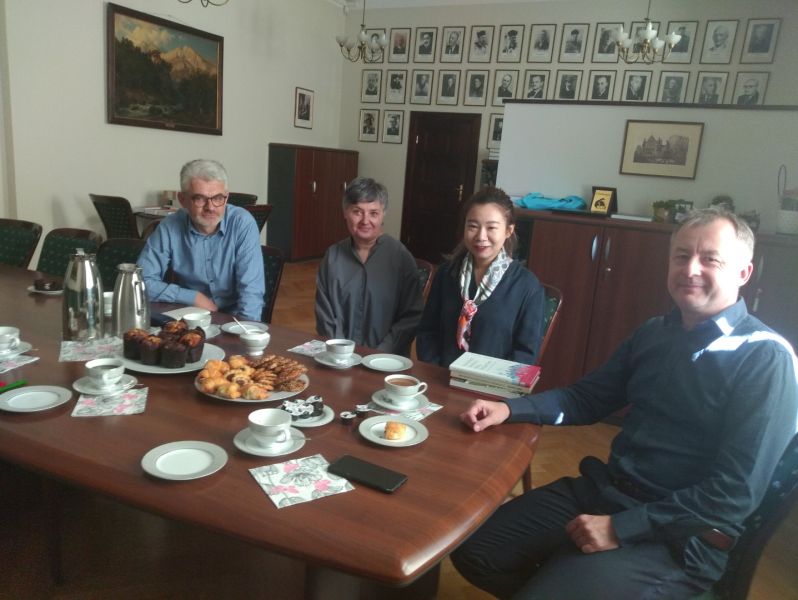 W gabinecie Dziekana przy stole siedzą cztery osoby: prof. Jerzy Borowczyk, dr Justyna Wciórka, dr Mao Rui i prof. Tomasz Mizerkiewicz. Stół zastawiony jest dzbankami z kawą i herbatą oraz słodkościami.