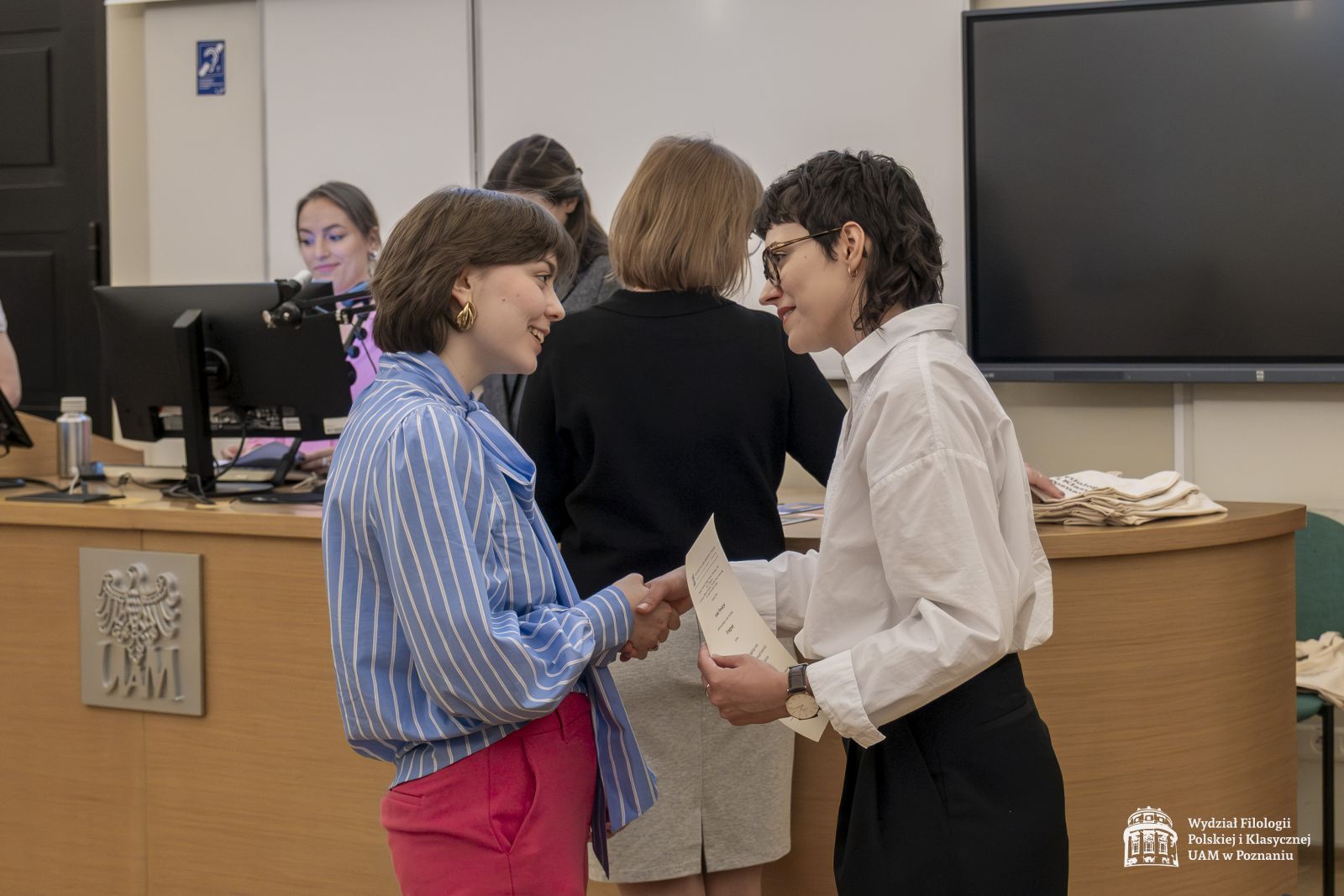 Dwie członkinie jury wręczają nagrody studentce.