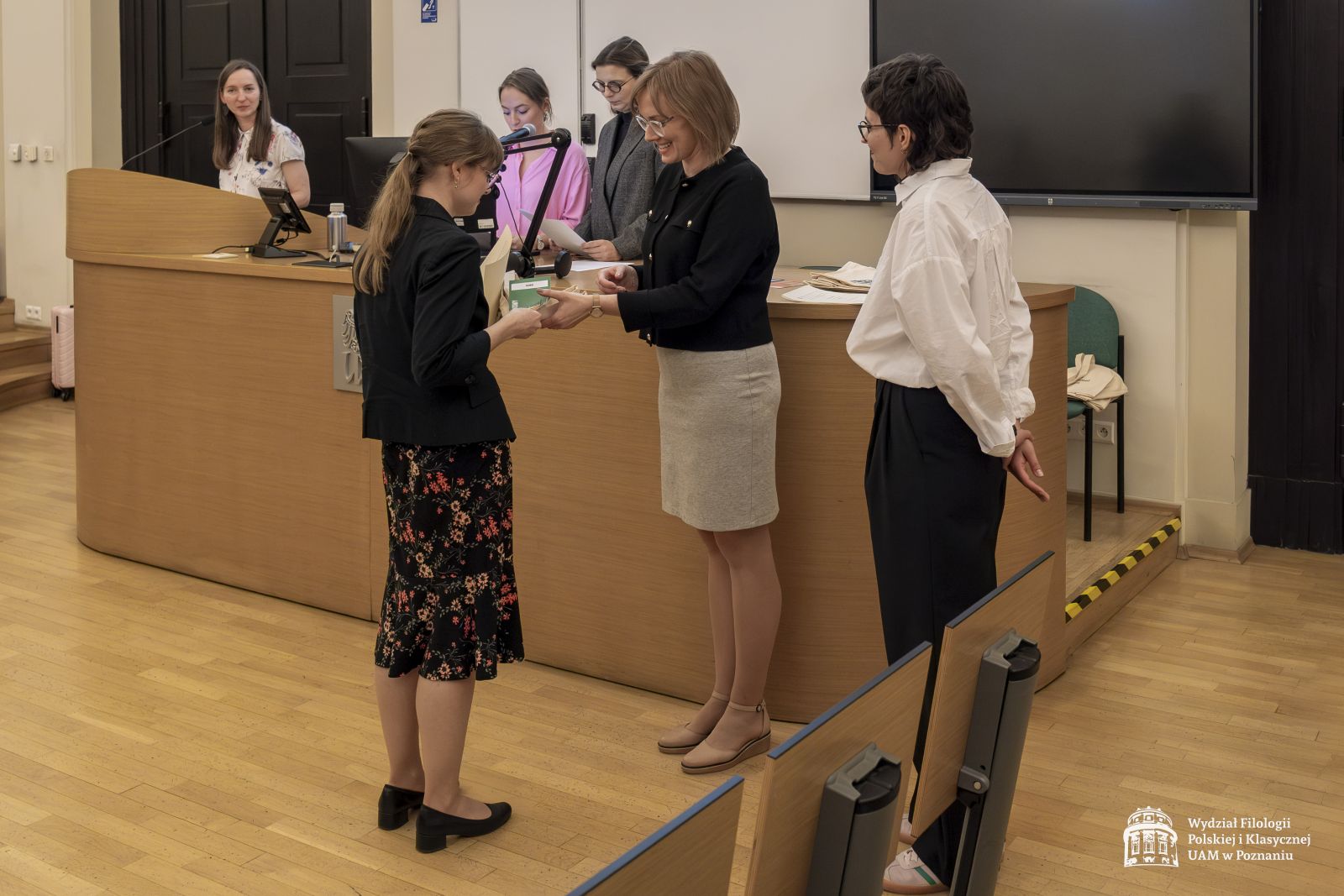 Dwie członkinie jury wręczają nagrody studentce.