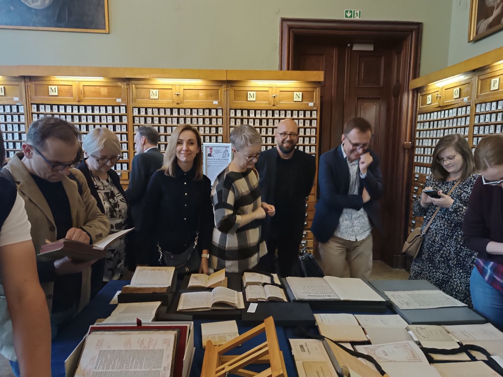 Uczestnicy Zjazdu w Bibliotece Uniwersyteckiej oglądają wystawione na stole starodruki.