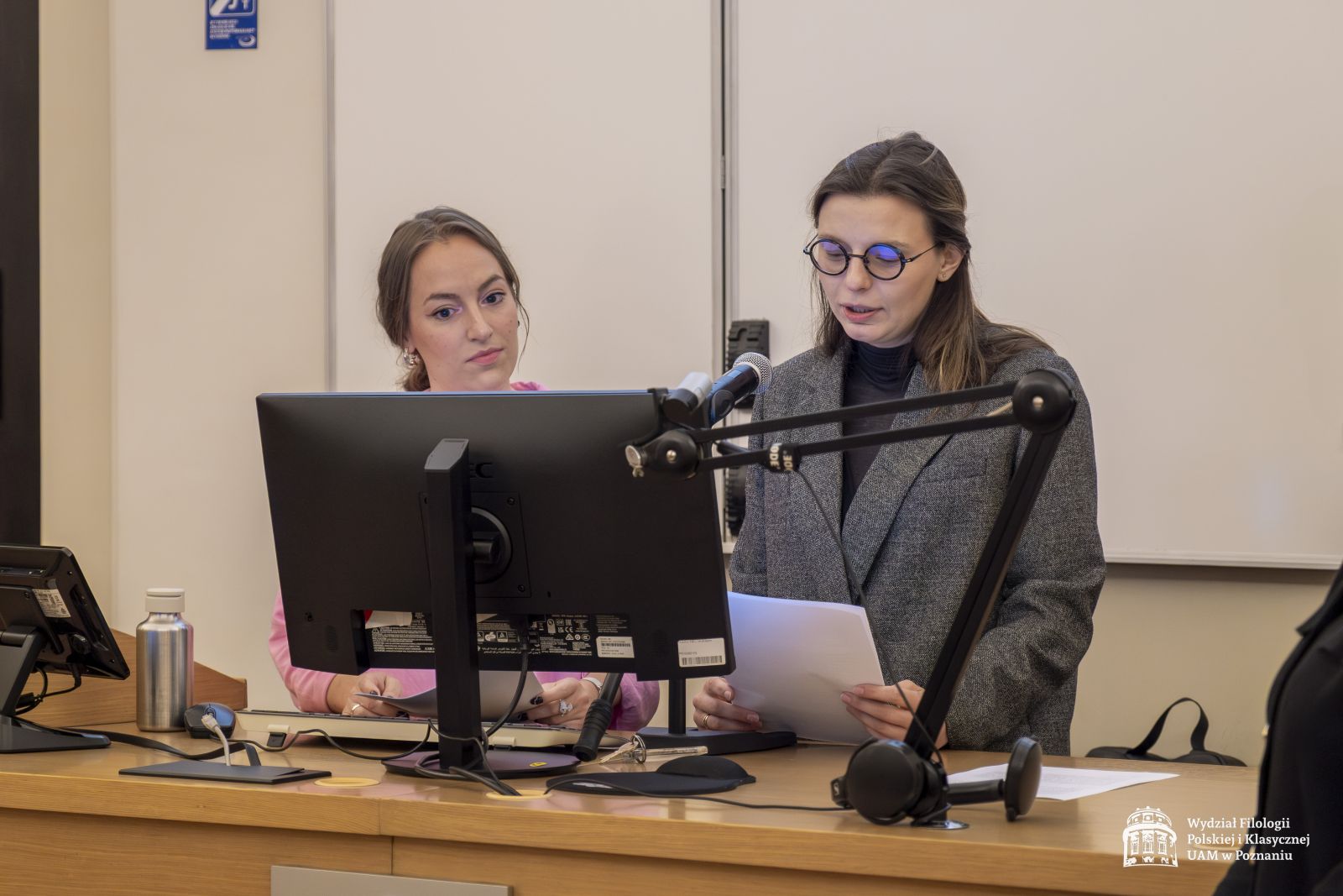Dr Aleksandra Sikorska-Krystek odczytuje laudację dla jednej z nagrodzonych osób. Obok niej stoi dr Adrianna Woroch.