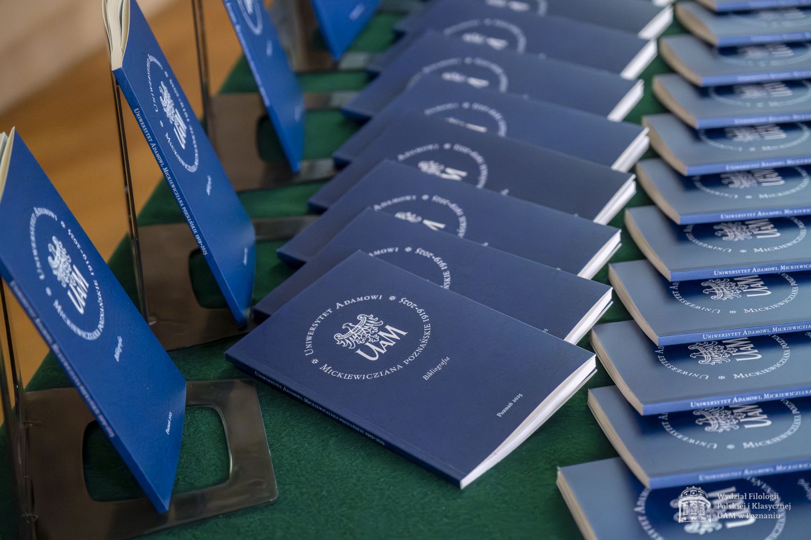 Wyłożone na stole przykrym zielonym suknem egzemplarze książki 