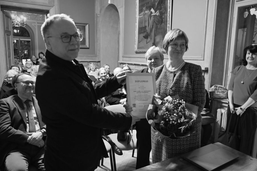 Czarno-białe zdjęcie prof. Okulicz-Kozaryna odbierającego dyplom.