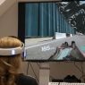 Uczestniczka warsztatów w okularach do VR gra w grę komputerową, która wyświetla się na ekranie telewizora.