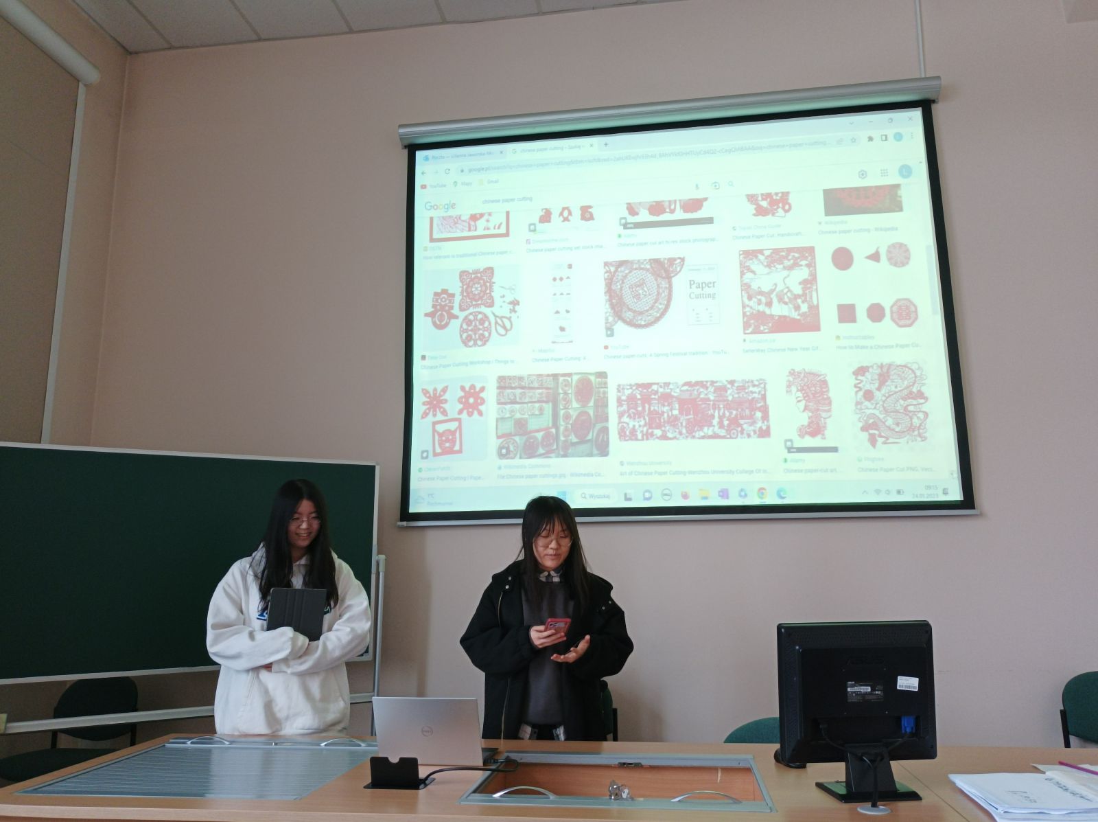 Studentki z Chin prezentuje tradycje związane z obchodami chińskiego Nowego Roku. Na rzutniku wyświetlają prezentację.