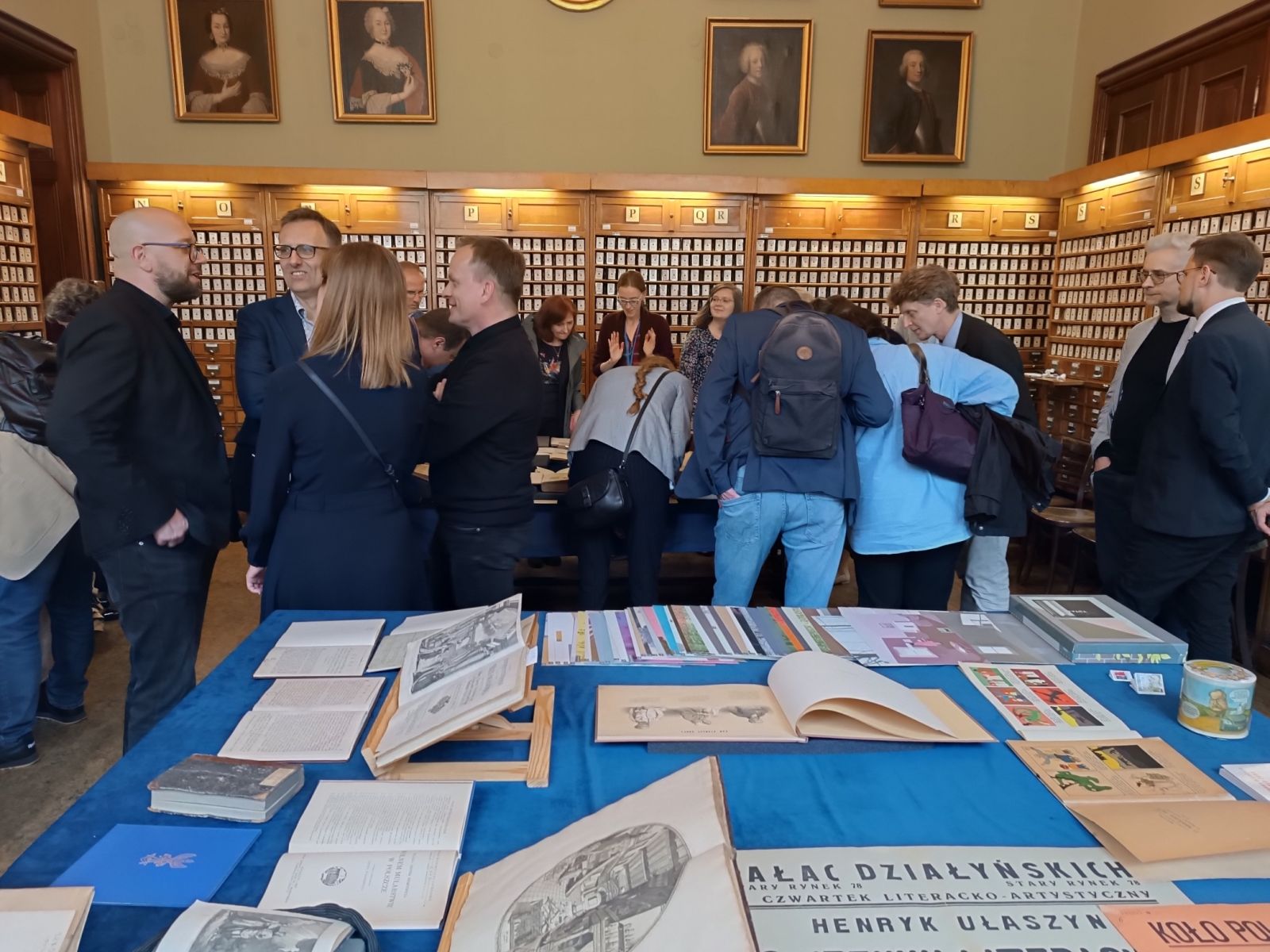 Uczestnicy Zjazdu w Bibliotece Uniwersyteckiej oglądają wystawione na stole starodruki.