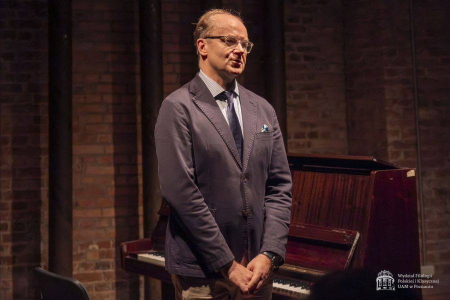 Prorektor Akademii Muzycznej w Poznaniu prof. Mikołaj Rykowski przemawia w Sali Teatralnej, stojąc obok fortepianu. 