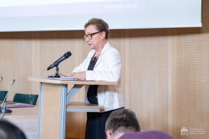 Prof. Mariola Mikołajczak odczytuje werdykt, stojąc przy mównicy w Salonie Mickiewicza.