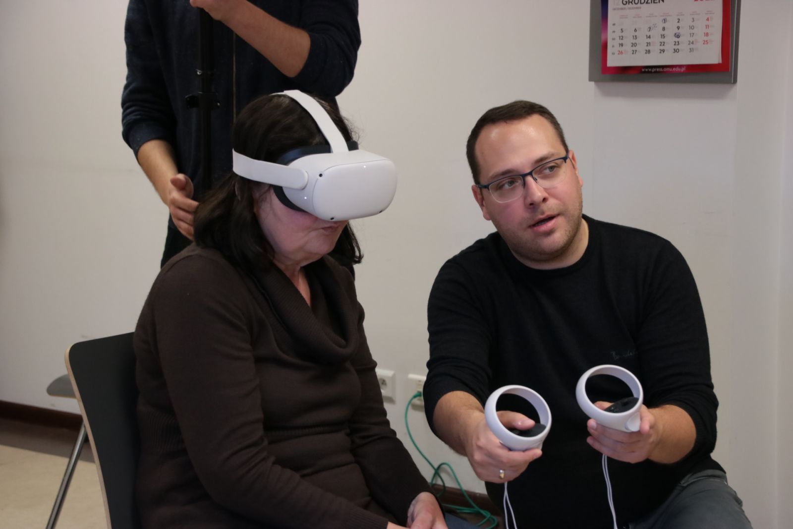 Prowadzący warsztaty objaśnia coś uczestniczce w okularach VR.