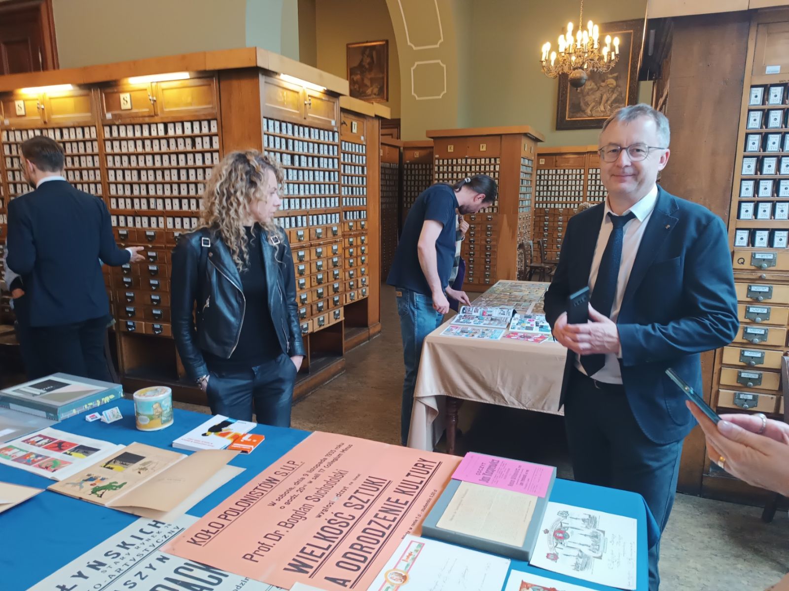 Uczestnicy Zjazdu w Bibliotece Uniwersyteckiej oglądają wystawione na stole starodruki.