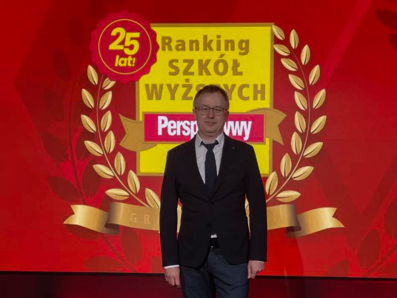 Dziekan WFPiK Tomasz Mizerkiewicz stoi na scenie, za nim wyświetla się grafika z napisem 