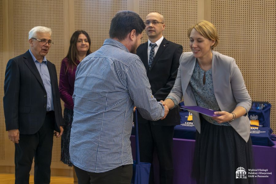 Student odbiera nagrodę w konkursie, ściska dłoń prodziekan ds. studenckich dr Urszuli Kowalskiej-Nadolnej, za nimi stoi: Dziekan WFPiK, prof. Jan Galant i dr Marlena Puk.