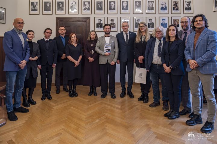Wspólne zdjęcie w gabinecie dziekańskim na tle wiszących na ścianach portretów poprzednich dziekanów.