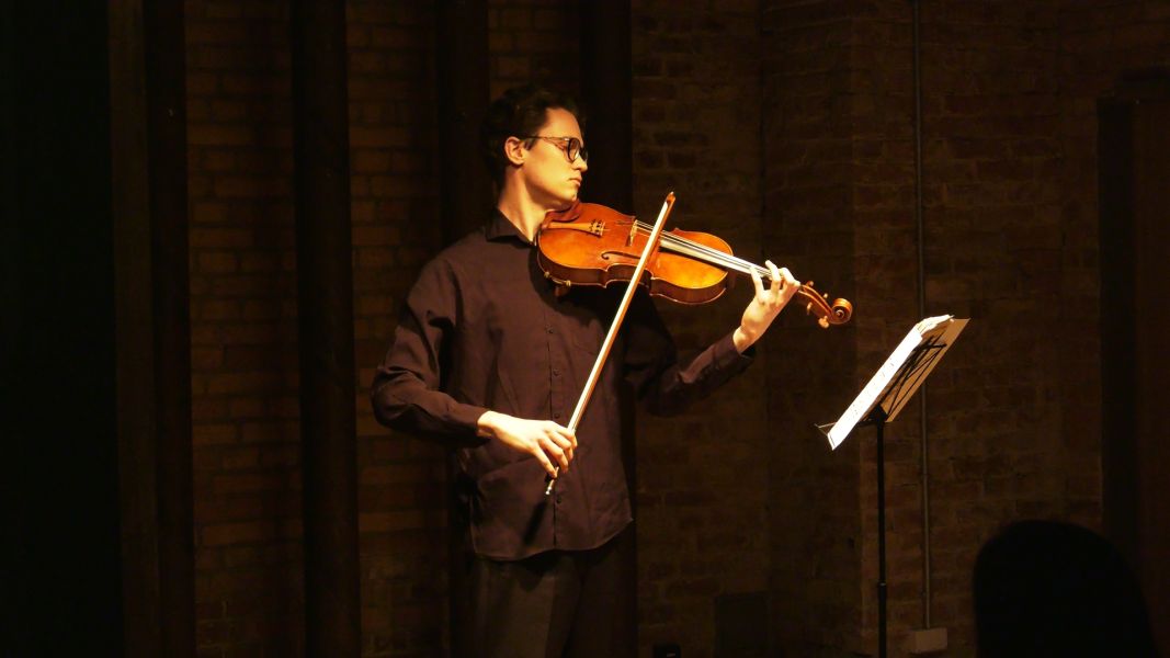 Altowiolista Paweł Drozdowski podczas koncertu w Sali Teatralnej. Przed nim stoi pulpit z nutami.