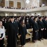 Uczestnicy absolutorium ubrani w togi i czapki absolwenckie siedzą w rzędach w Auli Uniwersyteckiej.