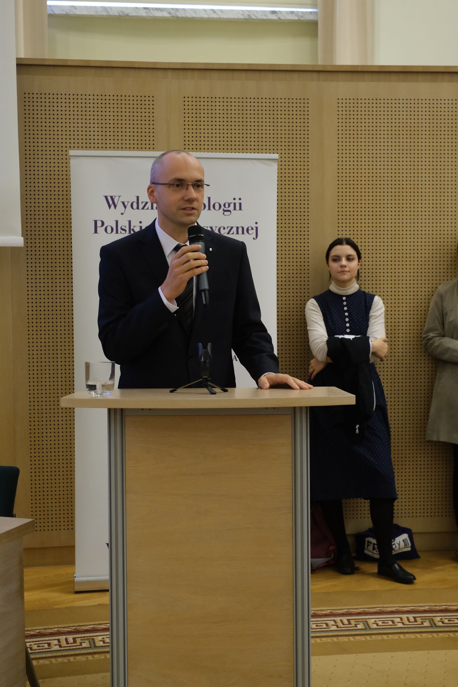 Prodziekan ds. studenkich i kształcenia, prof. UAM dr hab. Krzysztof Skibski stoi przy mównicy i przemawia do mikrofonu.