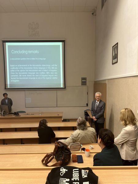 W sali wykładowej z rzędami pnących się ławek widać wyświetloną prezentację, a poniżej prelegenta - prof. Motoki Nomachiego.