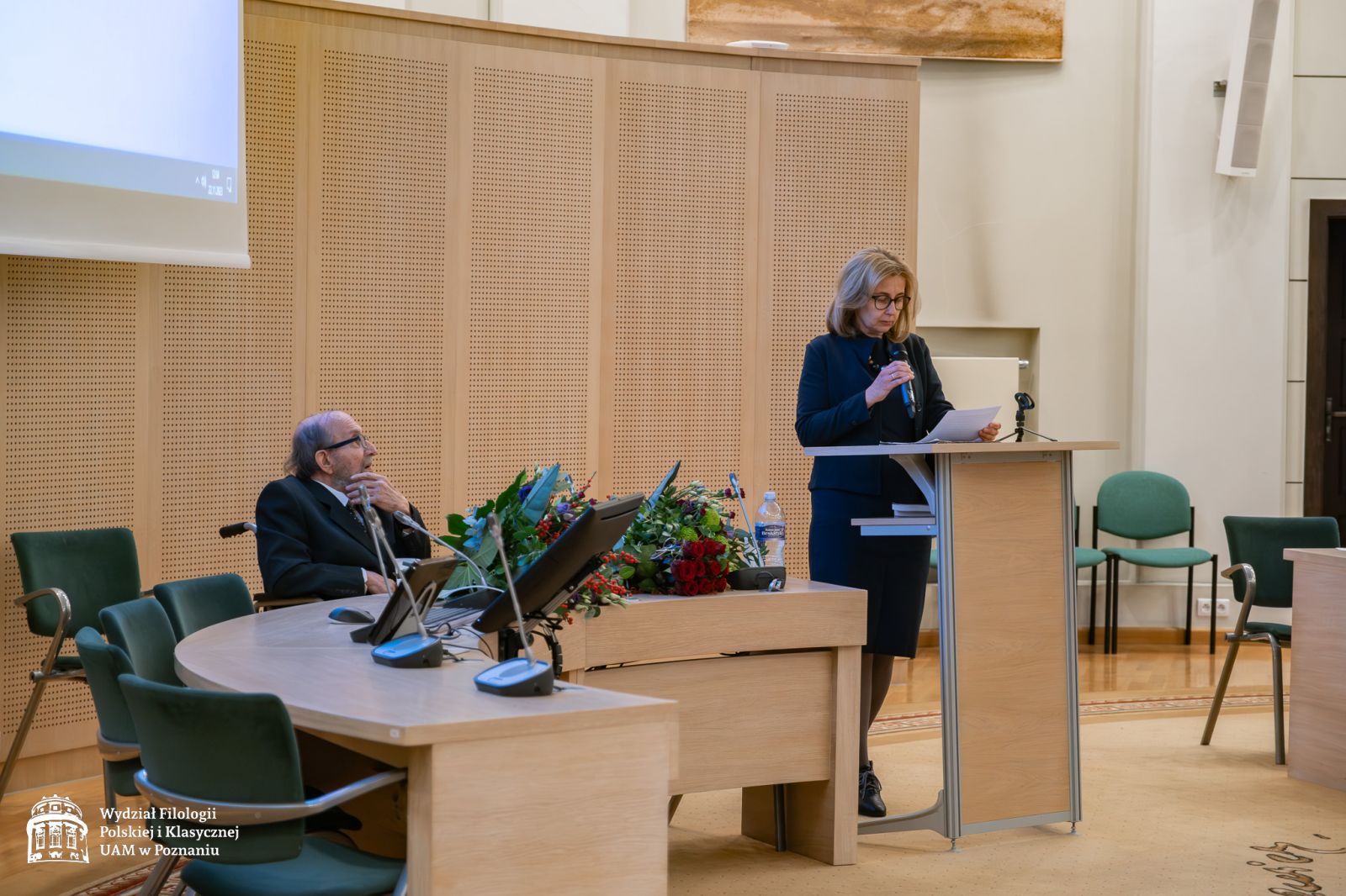 Prof. Małgorzata Okulicz-Kozaryn stoi przy mównicy, przemawia do mikrofonu.