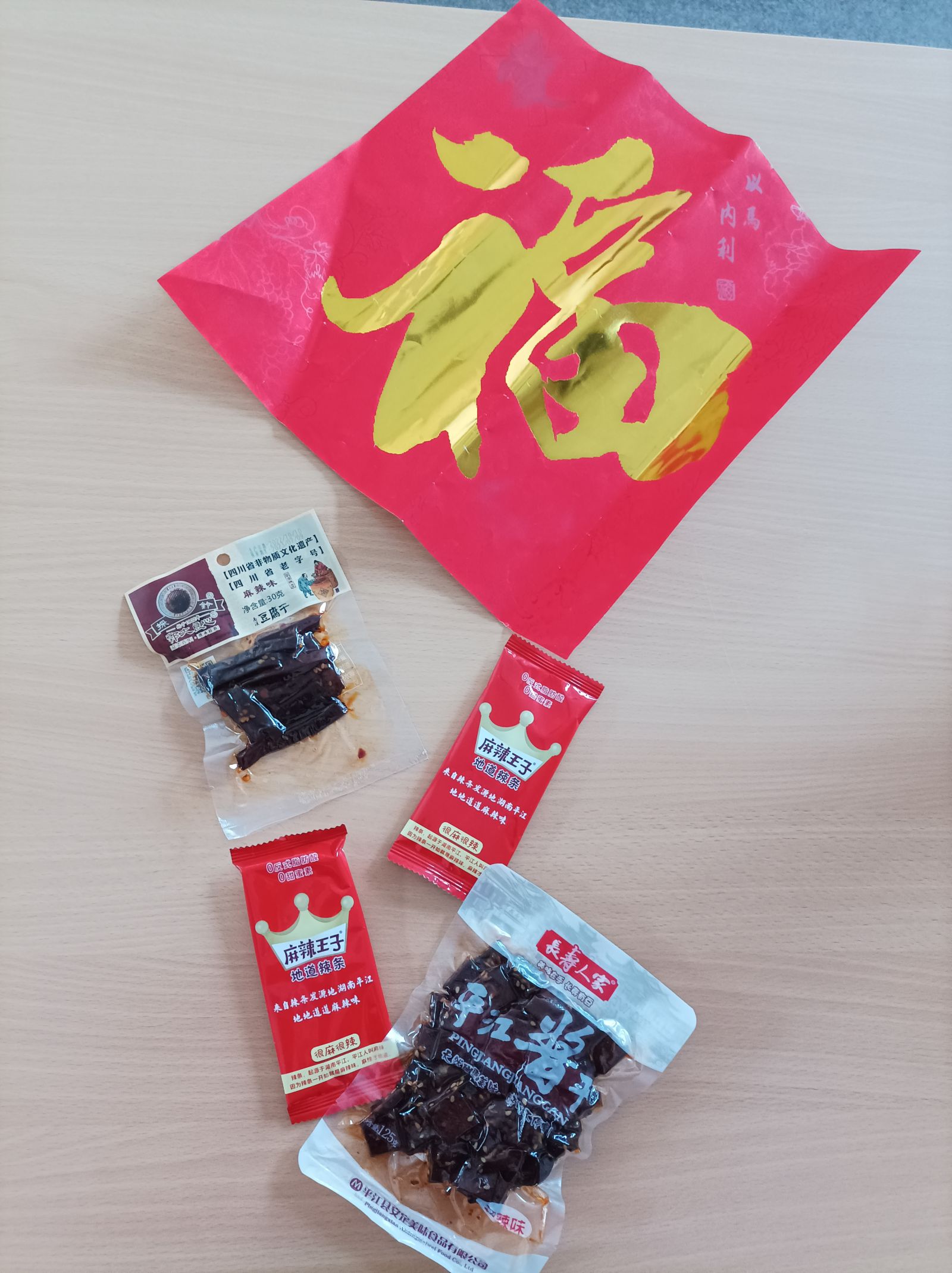 Przedmioty związane z obchodami chińskiego Nowego Roku - czerwona koperta, przysmaki w kolorowych saszetkach.