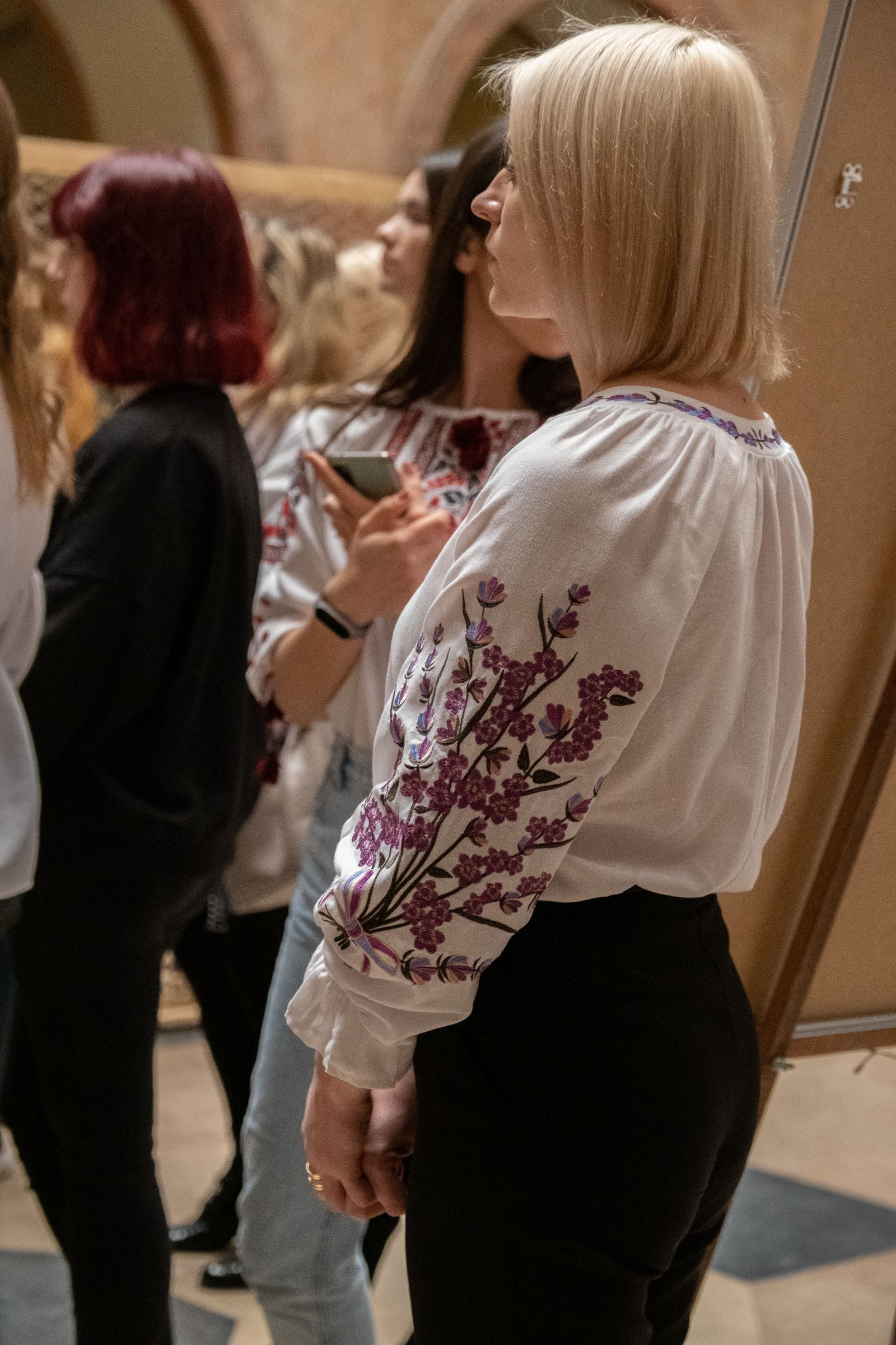Zbliżenie na młodą kobietę ubraną w białą bluzkę z tradycyjnym ukraińskim haftem.