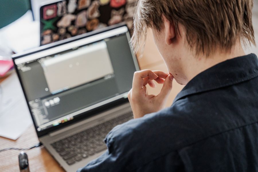Młody chłopak skupiony na ekranie laptopa.