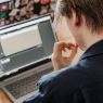 Młody chłopak skupiony na ekranie laptopa.