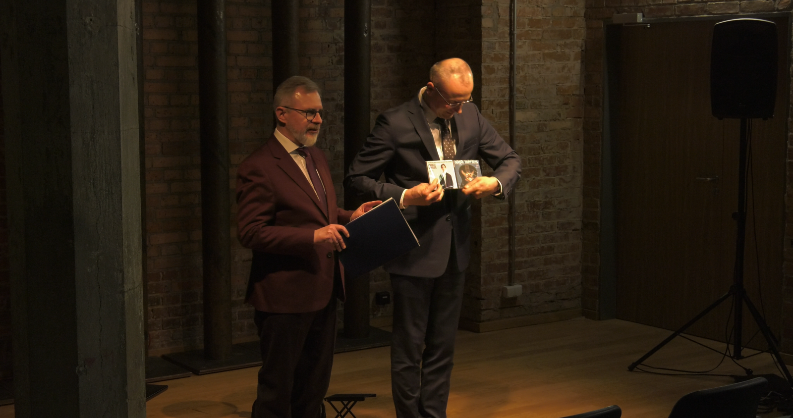 Dziekan WFPiK oraz prof. Piotr Urbański prezentują publiczności płyty gitarzysty Andrzeja Grygiera.