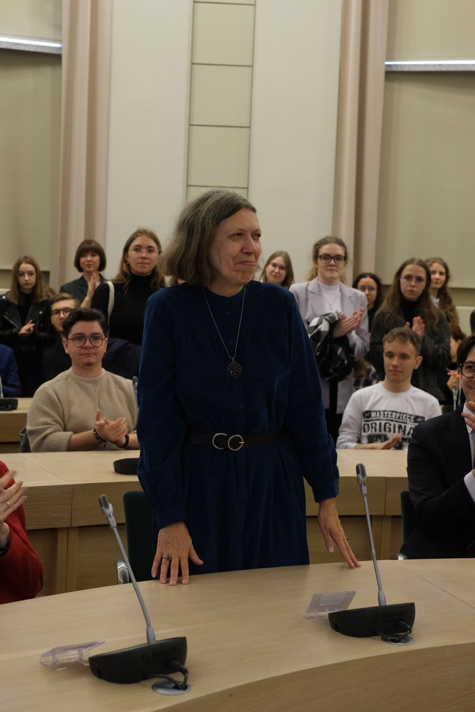Prof. Anna Gawarecka, Dyrektor Instytutu Filologii Słowańskiej, stoi za stołem, kłania się publiczności.