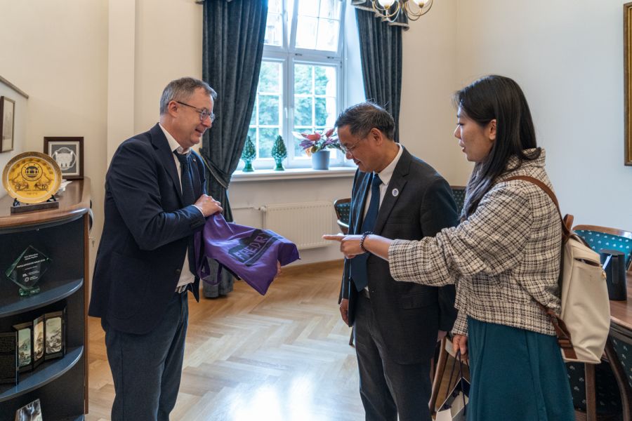 Dziekan WFPiK prezentuje torbę płócienną z logotypem Fredry 10, ogląda ją dwoje członków delegacji z Chin.