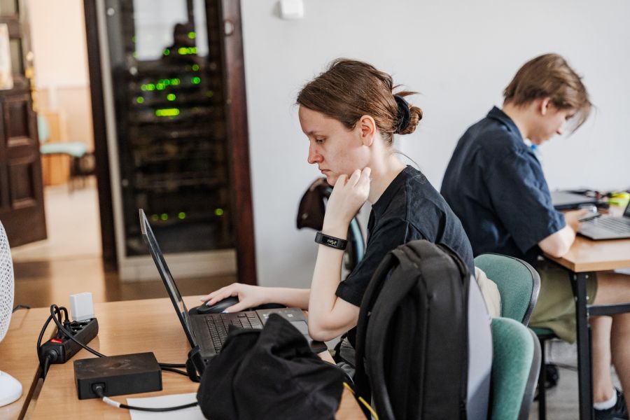 Dwie młode osoby siedzą przy laptopach, programując.