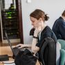 Dwie młode osoby siedzą przy laptopach, programując.