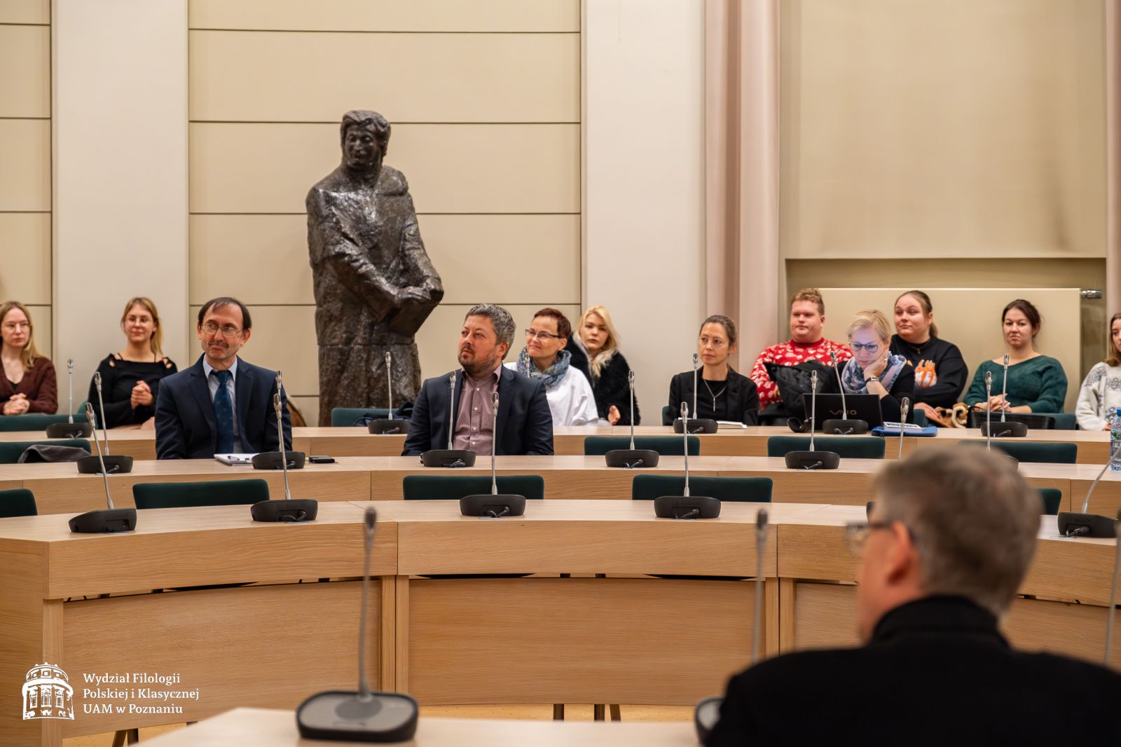 Widok ogólny na publikę zgromadzoną w Salonie Mickiewicza pod Kopułą, która siedzi przy długich, zakrzywionych w półkole stołach. W tle pomnik Adama Mickiewicza.