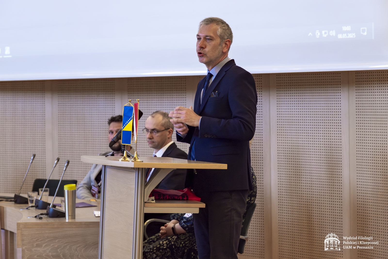 Prof. Sanjin Kodrić przemawia przy mównicy, obok widać stół prezydialny.